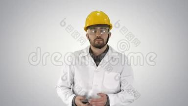 工程师戴着防护眼镜和帽子走路，在梯度背景上接电话。